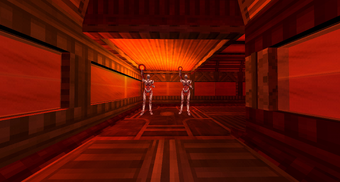 A hallway corner with two red humanoid creatures that look like the muscular system known as Strays charging up their Hell Energy Orb projectiles. The ceiling is lower above them.